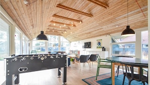 A spacious room with a foosball table, a dining table, and a TV on the wall. - 4 bedroom beautiful home in Vestervig (Vestervig)