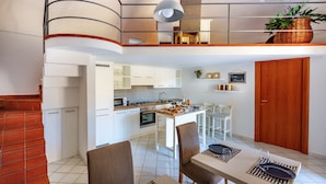A modern kitchen with white cabinets, a dining area with a table and chairs, and a staircase leading to an upper level. - Casa Assunta Sorrento Amalfi Coast, Vico Equense - free wifi (Vico Equense)