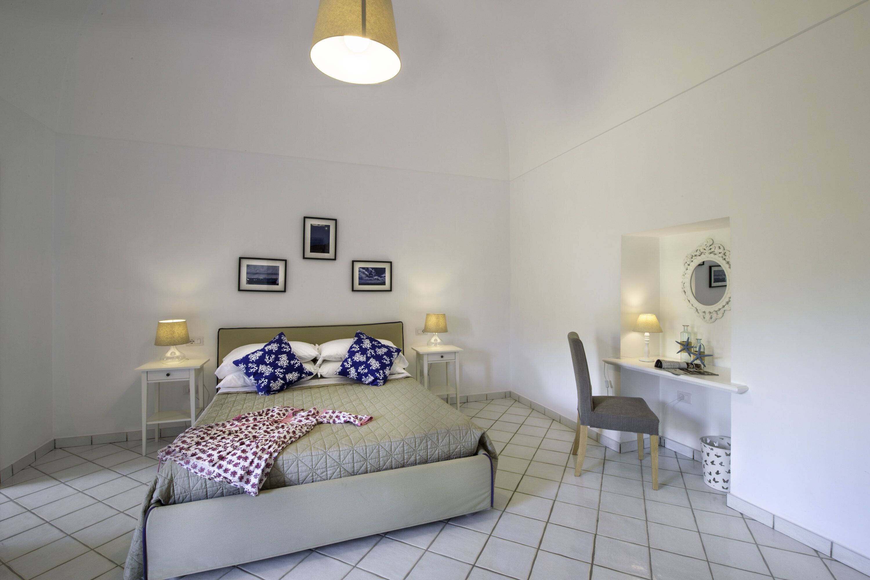 A bedroom with a bed, bedside tables, a desk, and a chair.