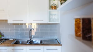 A modern kitchen with white cabinets, a stainless steel sink, and a wooden countertop. - Casa Assunta Sorrento Amalfi Coast, Vico Equense - free wifi (Vico Equense)