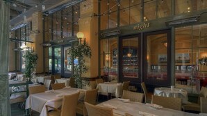 An indoor dining area with tables and wicker chairs, a large window with the word "light" on it, and a plant in the corner. - Santana Row Properties #7 - Silicon Valley Getaway (San Jose)