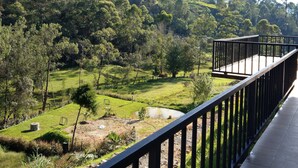 Un balcone con vista su un paesaggio verde lussureggiante e una collina sullo sfondo.