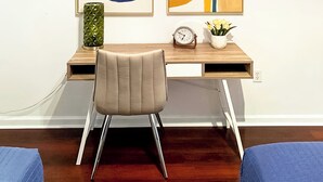 Een moderne kantoorruimte met een houten bureau, een leren stoel en twee abstracte schilderijen aan de muur.