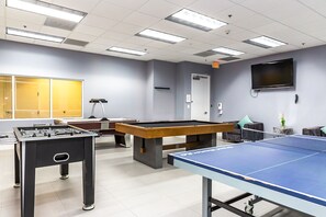 A room with a foosball table, pool table, ping pong table, and a TV mounted on the wall. - Brickell 1BR with Bay Views & Free Parking (Miami)