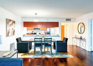 A modern kitchen with wooden cabinets, a dining area with a table and chairs, and a living room with a sofa and a coffee table.