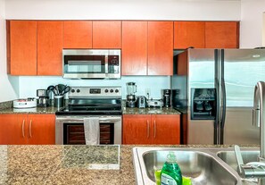 Eine Küche mit Holzausstattung, einem Edelstahlkühlschrank, einer Mikrowelle, einem Herd und einem Spülbecken.