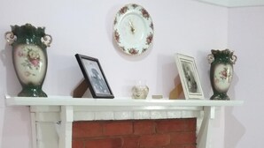 Une cheminée avec un foyer en briques, une cheminée blanche et un arrangement floral dans le foyer.