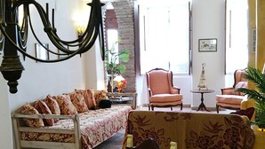 Una sala de estar acogedora con un sofá, sillones, una mesa de comedor y una araña.