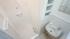 Een badkamer met een douche, een wastafel en een spiegel.