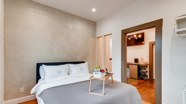 Ein Schlafzimmer mit Bett, Nachttisch und Blick in den Wohnbereich.
