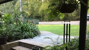 Un espace jardin aménagé avec des marches menant à une pelouse, entouré de différentes plantes et d’une clôture verte.