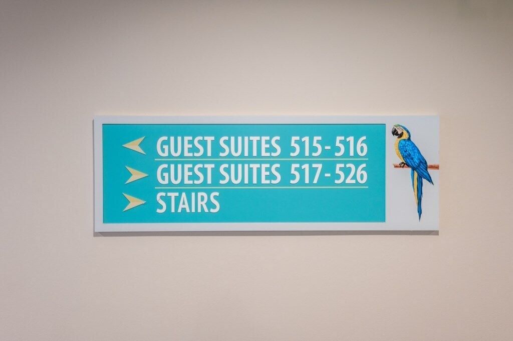 Un panneau de signalisation indiquant la direction des suites et des escaliers à l’aide de flèches.