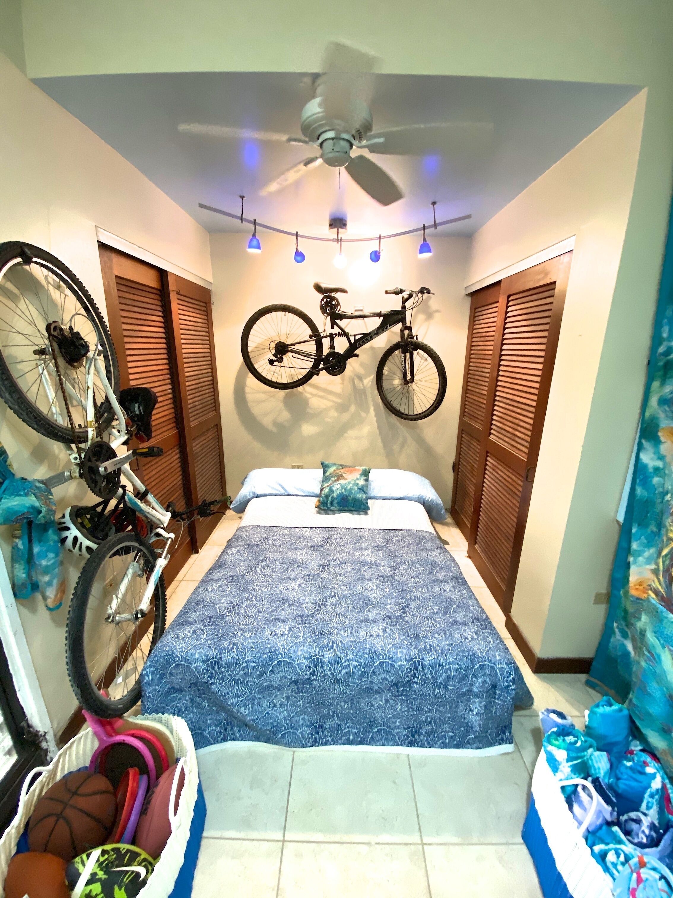 Une chambre à coucher avec un lit, un vélo fixé au mur et un porte-chaussures.