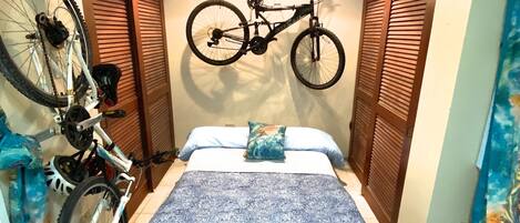Un dormitorio con cama, una bicicleta colgada en la pared y un zapatero.