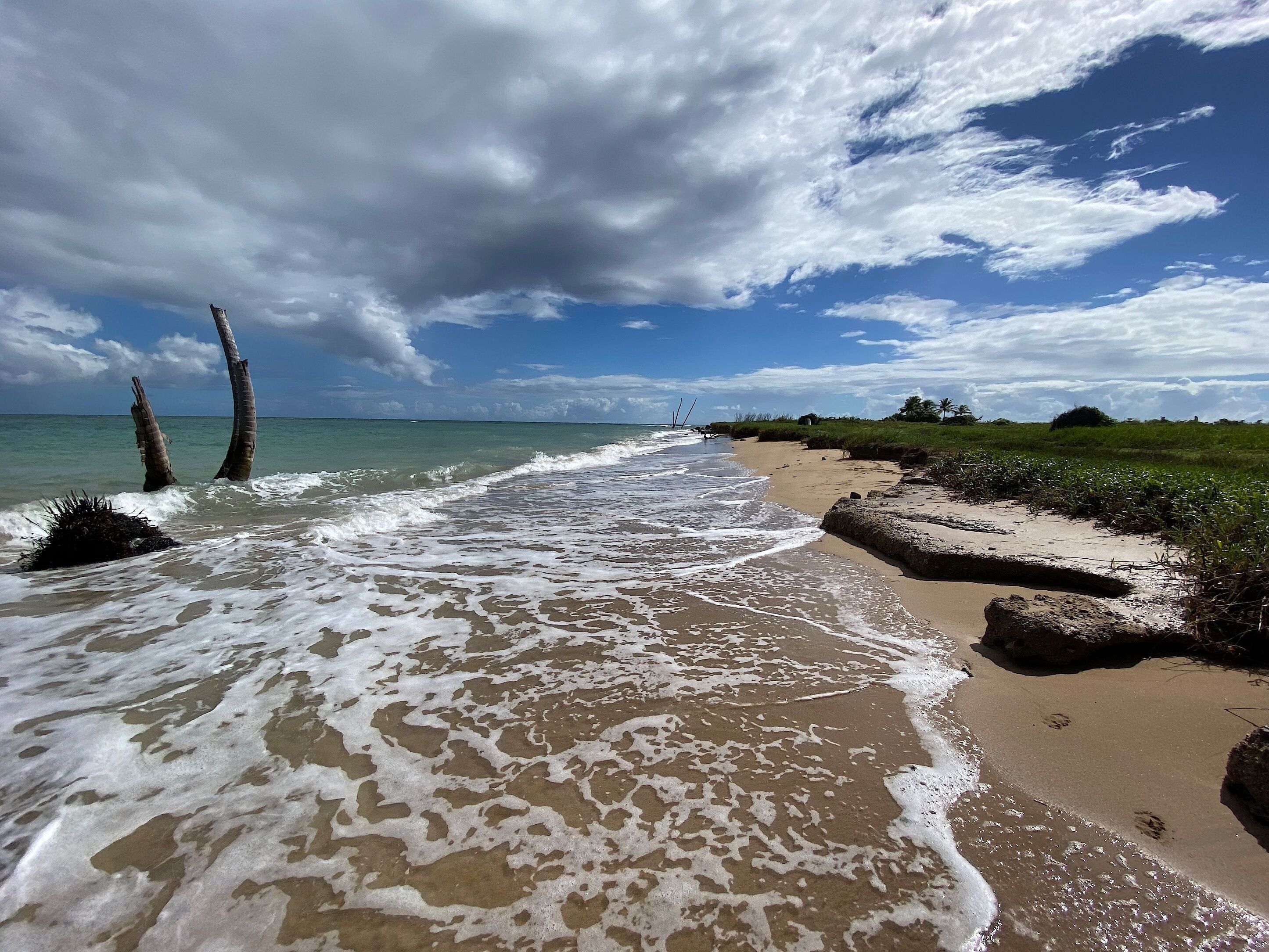 A beach with waves, a clear sky, and a distant view of a structure.
