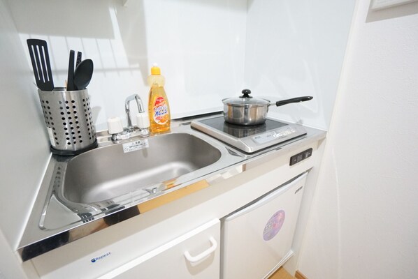 Efficient kitchenette with a stainless steel sink, stove, and utensil holder.