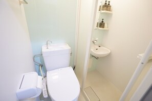 A small, clean bathroom with a toilet, bidet, and sink. - Terry's Apartment Namba South V C02E (Osaka)