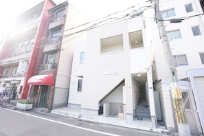 Stylish building with a brick and white exterior, featuring a main entrance and a shop on the ground floor.