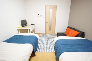A hotel room with two beds, a desk, a chair, and a computer. - Terry's Apartment Namba South V C02E (Osaka)