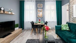 Een moderne woonkamer met een televisie, eettafel, stoelen en een bank.