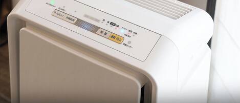 Purificador de aire blanco con panel de control que presenta texto en japonés y un botón de encendido.