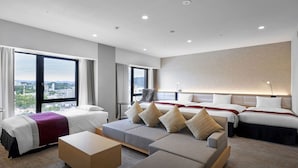 Habitación de hotel con dos camas, un sofá, una mesa de centro y vistas a la ciudad.