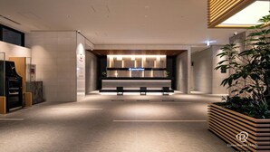 Un moderno vestíbulo de hotel con mostrador de recepción, zona de estar y una planta grande.