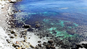 Un rivage rocheux bordé d’une eau d’un bleu limpide.