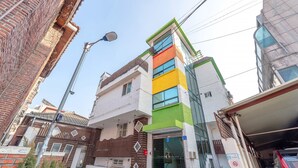 A multi-story building with a mix of brick and modern glass facades, a visible entrance, and a street lamp. - SeeU House (Seoul)