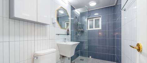 A bathroom with a white toilet, a sink, and a shower.
