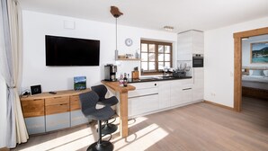 Eine moderne Küche mit Flachbildfernseher, Holzschränken und einem Barhocker.