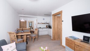 A compact living space with a dining area, kitchenette, and a TV.
