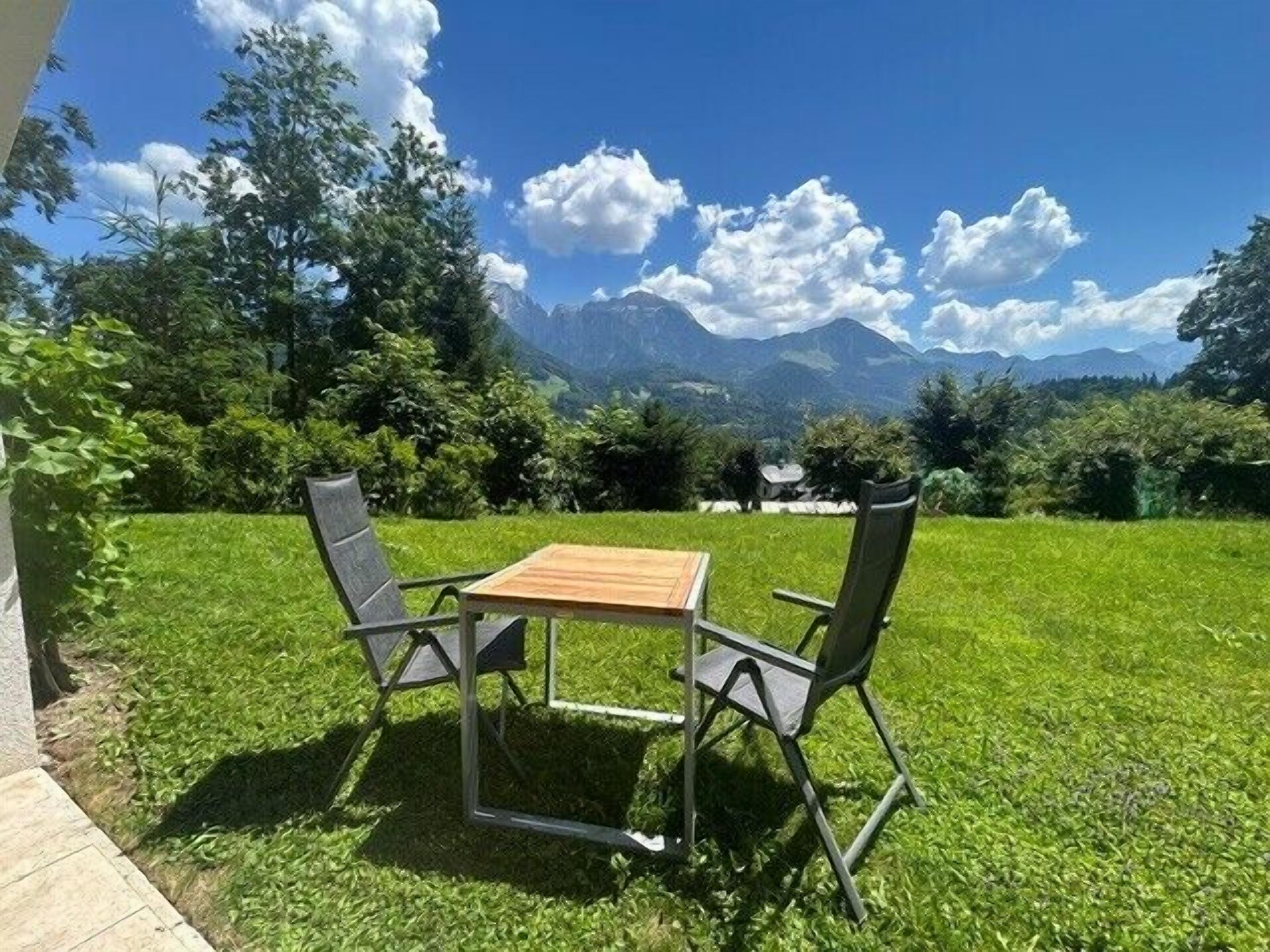 Une table et des chaises sont disposées sur une pelouse verdoyante, avec une vue sur les montagnes.