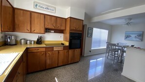 A kitchen with wooden cabinets, a granite countertop, and a dining area with a table and chairs.