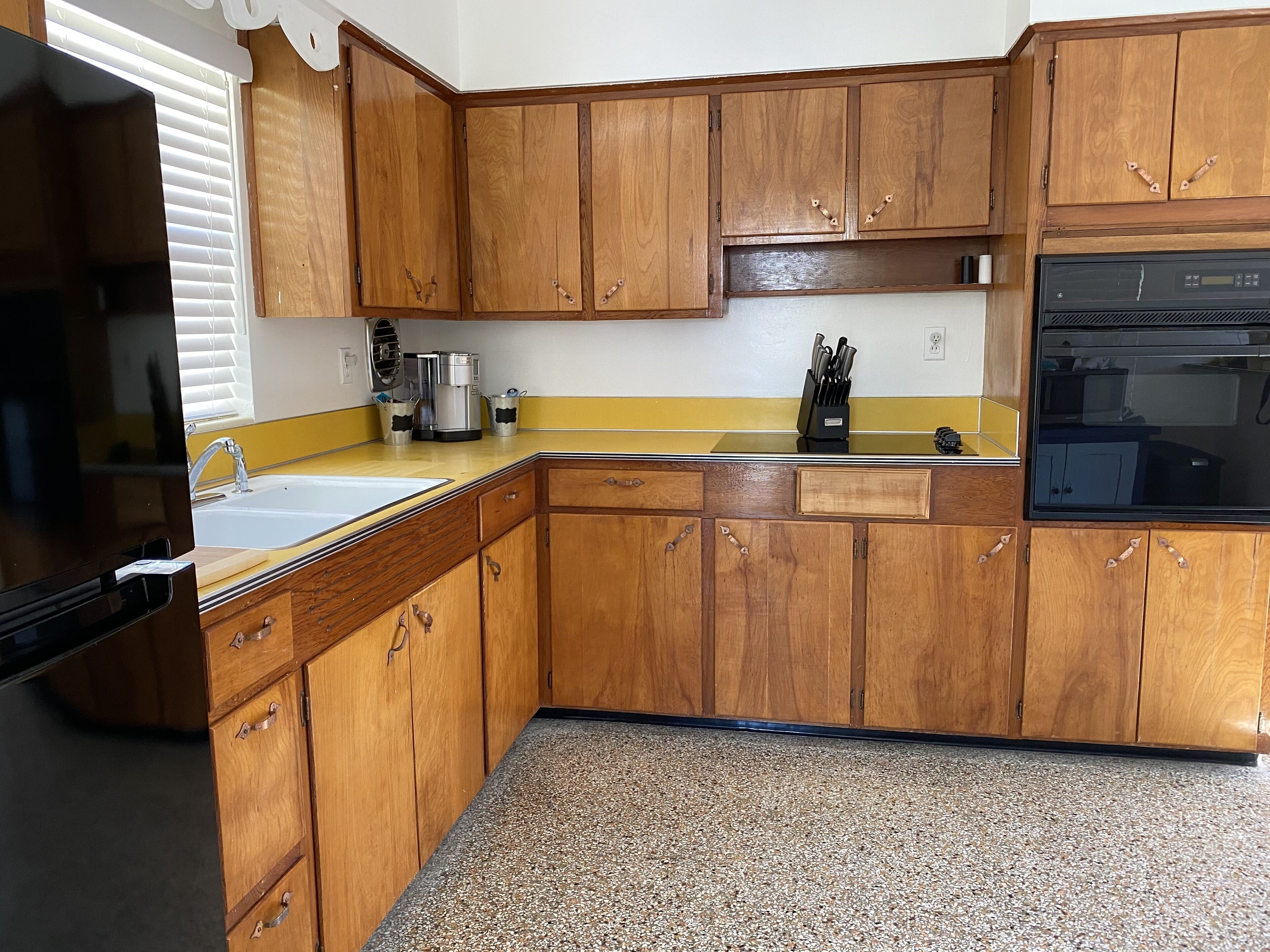 Una cocina con armarios de madera, un lavabo, una estufa y una cafetera.