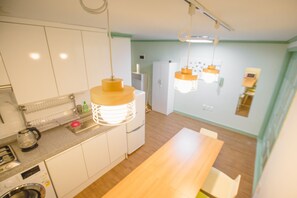 A modern kitchen with white cabinets, a wooden countertop, and pendant lighting.