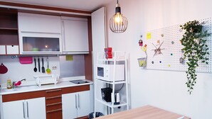 A modern kitchen with white cabinets, a wooden countertop, a sink, and a dining area with a table and chairs. - Sweet House (Seoul)