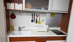 A compact kitchenette with a sink, a stove, and a microwave. - Sweet House (Seoul)