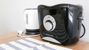 A black Electrolux toaster on a wooden table with a white appliance in the background. - Sweet House (Seoul)