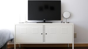 A white cabinet with a flat-screen TV and a round mirror on top. - Sweet House (Seoul)