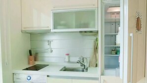 A compact kitchen with a built-in washing machine, a sink, and a microwave. - Sweet House2 (Seoul)