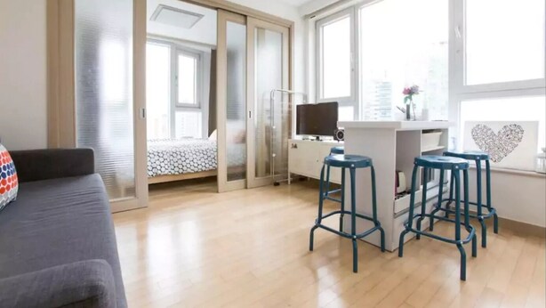 A modern apartment with a sofa, a desk with a computer, and a bar stool area. - Sweet House2 (Seoul)