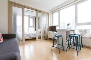 A modern apartment with a sofa, a desk with a computer, and a bar stool area. - Sweet House2 (Seoul)