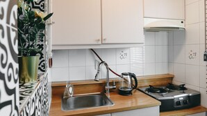 Et moderne køkken med hvide skabe, en træbordplade, en elkedel og en komfur.