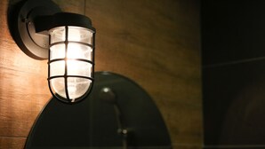 En vægmonteret lampe med cylinderformet design og et gittermønster.