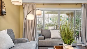 A living room with grey sofas, a wooden coffee table, and a potted plant. - Condo with Open Access to the Scenery from Ground Porch (Kissimmee)