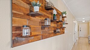 A hallway with a wooden wall panel and shelves holding various decorative items. - Condo with Open Access to the Scenery from Ground Porch (Kissimmee)