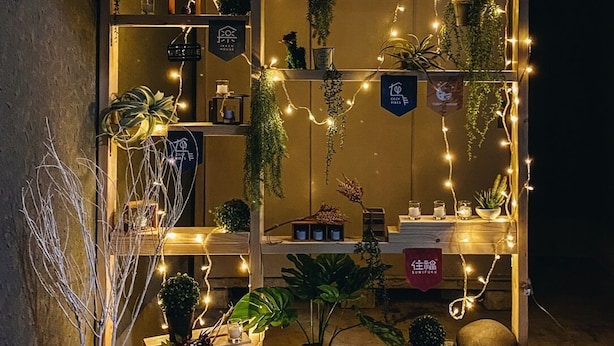 A cozy outdoor seating area with string lights, potted plants, and a wooden bench. - Ikken Rakutei (Tokyo)
