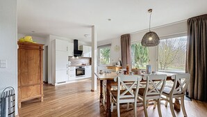 Una cocina moderna con armarios blancos, una mesa de comedor de madera y sillas.