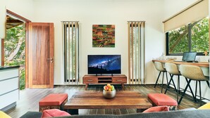 A modern living room with a wooden coffee table, a flat-screen TV, and a dining area with chairs. - Ranis Lodge (Langkawi)